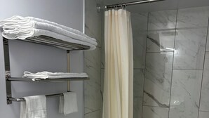 Ein Badezimmer mit Toilette, Duschvorhang und Handtüchern an einem Haken.