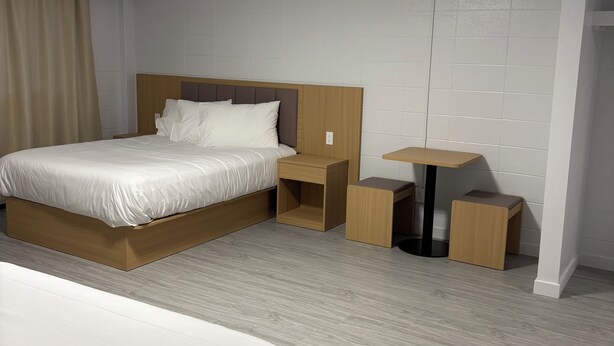 Ein Hotelzimmer mit zwei Betten, einem Nachttisch, einem kleinen Tisch und einer Deckenleuchte.