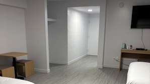 A hotel room with a bed, a desk, a TV, and a bathroom visible in the background. - Rundle Inn and Suites (Edmonton)