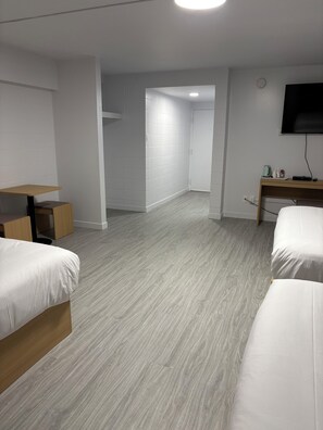 Una habitación de hotel con una cama, un escritorio, un televisor y un baño a la vista.