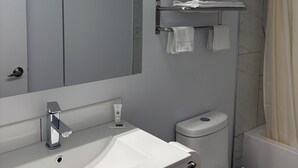 Ein modernes Badezimmer mit großem Spiegel, Waschbecken in Weiß, Toilette und Duschvorhang.