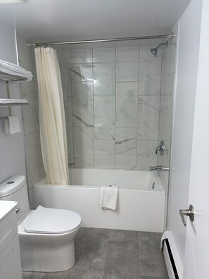 A bathroom with a shower, toilet, and towel rack.