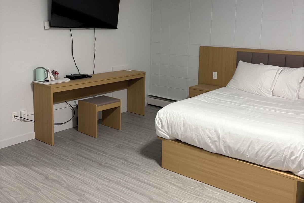 Un dormitorio con cama, escritorio y televisor.