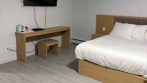 A bedroom with a bed, a desk, and a TV. - Rundle Inn and Suites (Edmonton)