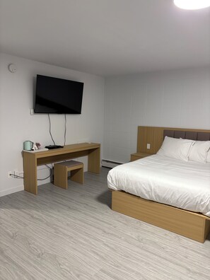 Un dormitorio con cama, escritorio y televisor.