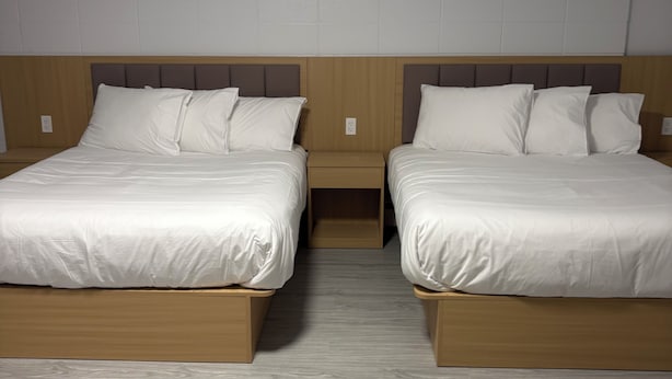 A hotel room with two beds, wooden headboards, and a light-colored wooden floor. - Rundle Inn and Suites (Edmonton)