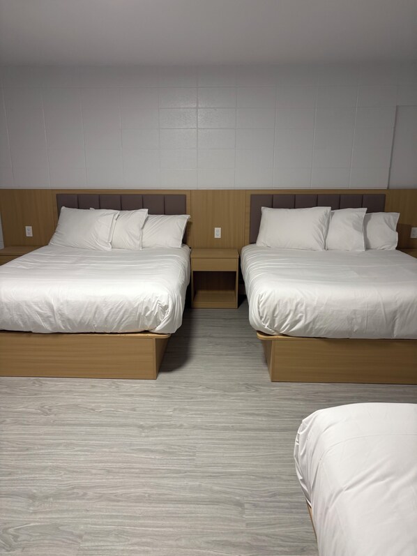 Habitació d'hotel amb dos llits, capçals de fusta i un sòl de fusta de color clar.