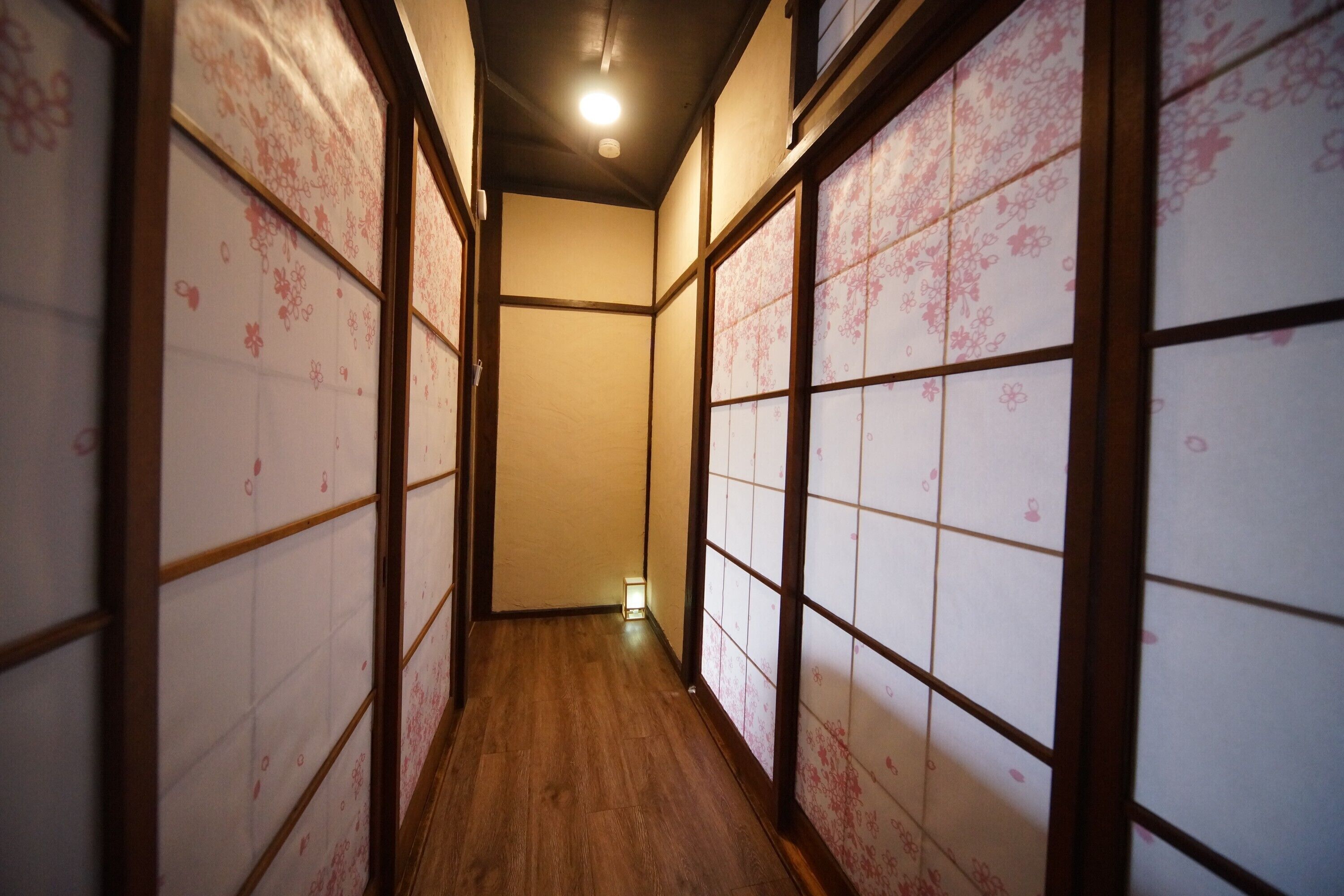 A narrow hallway with wooden flooring and traditional sliding doors with floral patterns.