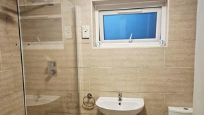 Une salle de bain avec une douche à parois de verre, un lavabo sur colonne et des toilettes.