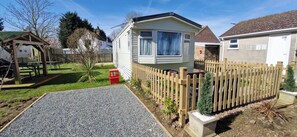 A caravan with a fenced garden, a gravel path, and a picnic table. - Fieldview Lodge Dog Friendly nr Anderby Creek (Alford)