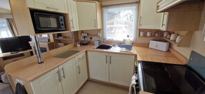 A compact kitchen with a microwave, toaster, sink, and stove. - Fieldview Lodge Dog Friendly nr Anderby Creek (Alford)