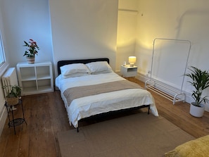 Ein ordentlich eingerichtetes Schlafzimmer mit Bett, Nachttischen, Heizkörper und Fenster.