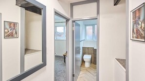 A hallway with a door leading to a bathroom with a toilet and a mirror. - Apartment Sleeps 8 with WiFi (Nottingham)