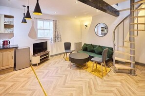 A modern living room with a herringbone floor, a sofa, a TV, and a staircase. - Apartment Sleeps 8 with WiFi (Nottingham)