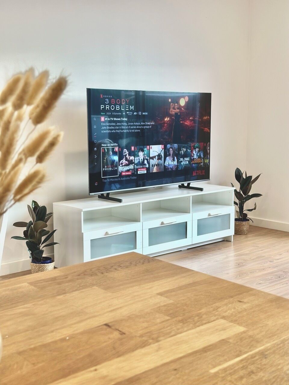 A flat-screen TV on a white TV stand with a wooden floor.