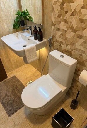 Une salle de bain moderne avec un lavabo, des toilettes et une douche, le tout de couleur blanche.