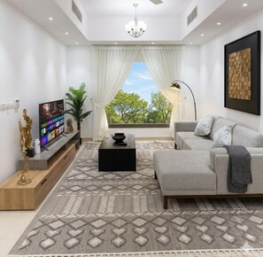 Ein modernes Wohnzimmer mit Flachbildfernseher, einer Couch, einem Couchtisch und einem gemusterten Teppich.