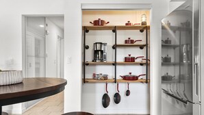 Une cuisine moderne équipée d’un four encastré, d’une machine à café et de différents ustensiles de cuisine rangés sur des étagères.