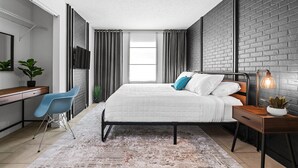 Une chambre à coucher moderne avec un lit, un bureau, une chaise et une table de chevet.