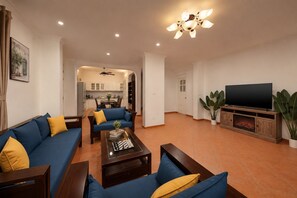 Ein Wohnzimmer mit einer Couch, einem Couchtisch, einem Fernseher und einer Küche im Hintergrund.
