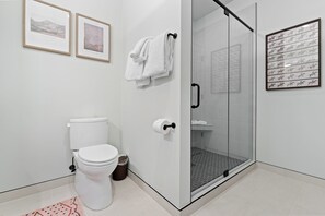 Une salle de bain moderne avec des toilettes, une douche en verre et des tableaux encadrés accrochés au mur.