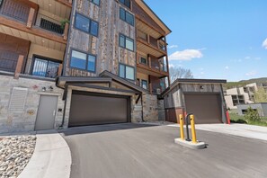 A multi-story building with balconies, a garage, and a stone facade. - New Designer Condo-King Bed, Pool/HT, Spa, Lake (Keystone)