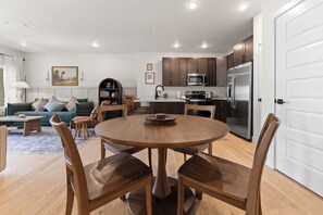Une cuisine moderne avec un îlot central, une table à manger en bois et des chaises.