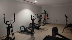 Ett rum med träningsutrustning, inklusive en motionscykel, en crosstrainer och en roddmaskin.