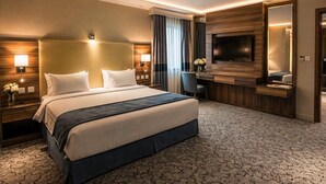 Ett modernt hotellrum med en stor säng, ett skrivbord, en platt-TV och en spegel.