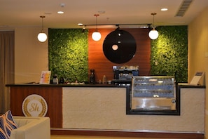 Una zona de recepción con una pared verde, una máquina de café y un mostrador.