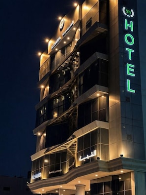 Ein mehrstöckiges Hotel mit beleuchteter Beschilderung, Balkonen und modernem Architekturstil.