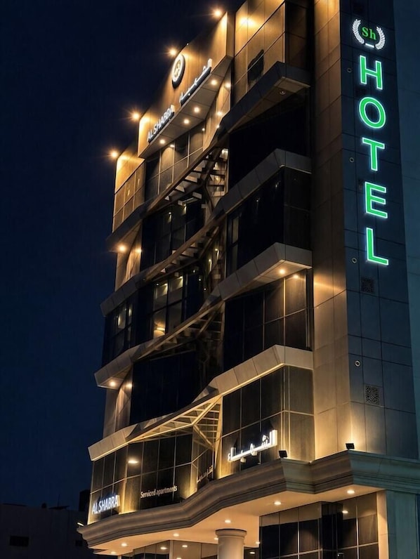 Un hotel de varios pisos con señalización iluminada, balcones y un diseño arquitectónico moderno.