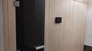 Una habitación con puerta corrediza, panel de control en la pared y suelo de baldosas.