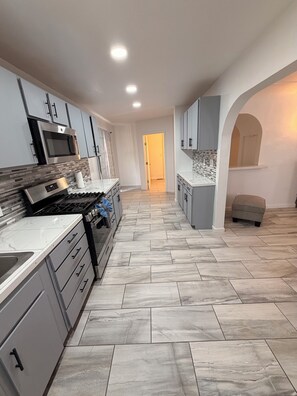 A modern kitchen with grey cabinets, a built-in oven, and a tiled floor.