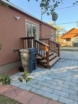 A residential building with a wooden deck, a trash bin, and a satellite dish.