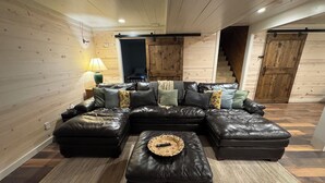 Ein modernes Wohnzimmer mit einer Eckcouch, einem Hocker und einer Lampe.