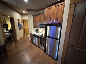 A kitchen with wooden cabinets, stainless steel appliances, and a wooden floor. - 4th July Family Vacation 4-bedroom Resort Cabin with Mountain view & Water Park (Gatlinburg)