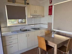 A kitchen with a window, sink, cabinets, and a dining table with chairs.