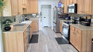 Eine moderne Küche mit Holzausbau, Edelstahlgeräten und einer schwarzen Arbeitsplatte.