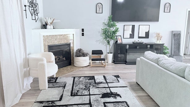 Ein modernes Wohnzimmer mit Kamin, großem Fernseher und einer Couch.