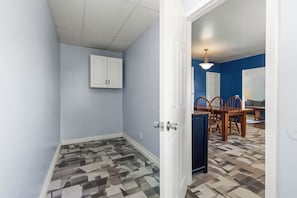 A room with a geometric patterned floor, a white door, and a dining area with a table and chairs.
