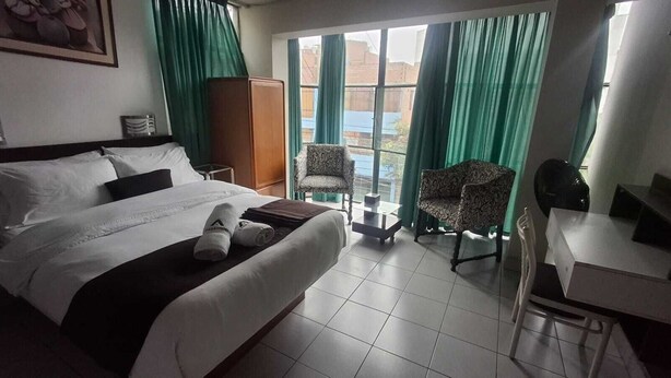 A hotel room with a bed, a desk, a chair, and a view through the window. - GrupoCasahotel Accommodation 5 minutes away from Jockey Plaza, Rambla, Museo de Nación (Ate)