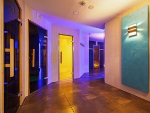 Ein moderner Hotelgang mit Glastür, blauer Akzentwand und Fliesenboden.