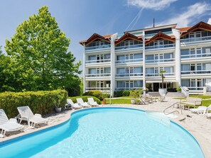 Ein Hotel mit Pool, mehreren Balkonen und einem gepflegten Garten.