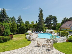 Ein Garten mit Swimmingpool, Liegestühlen und einer Steinterrasse.