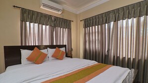A hotel room with a large bed, curtains, an air conditioning unit, and a headboard. - Hotel Lekali Homes  (Kathmandu)