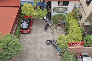 Un estacionamiento con un coche rojo, un scooter negro y un coche azul.
