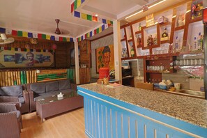 A bar area with a counter, seating, and various items on shelves. - Hotel Lekali Homes  (Kathmandu)