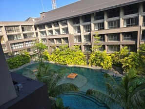 Un hotel moderno con piscina rodeada de exuberante vegetación y palmeras.