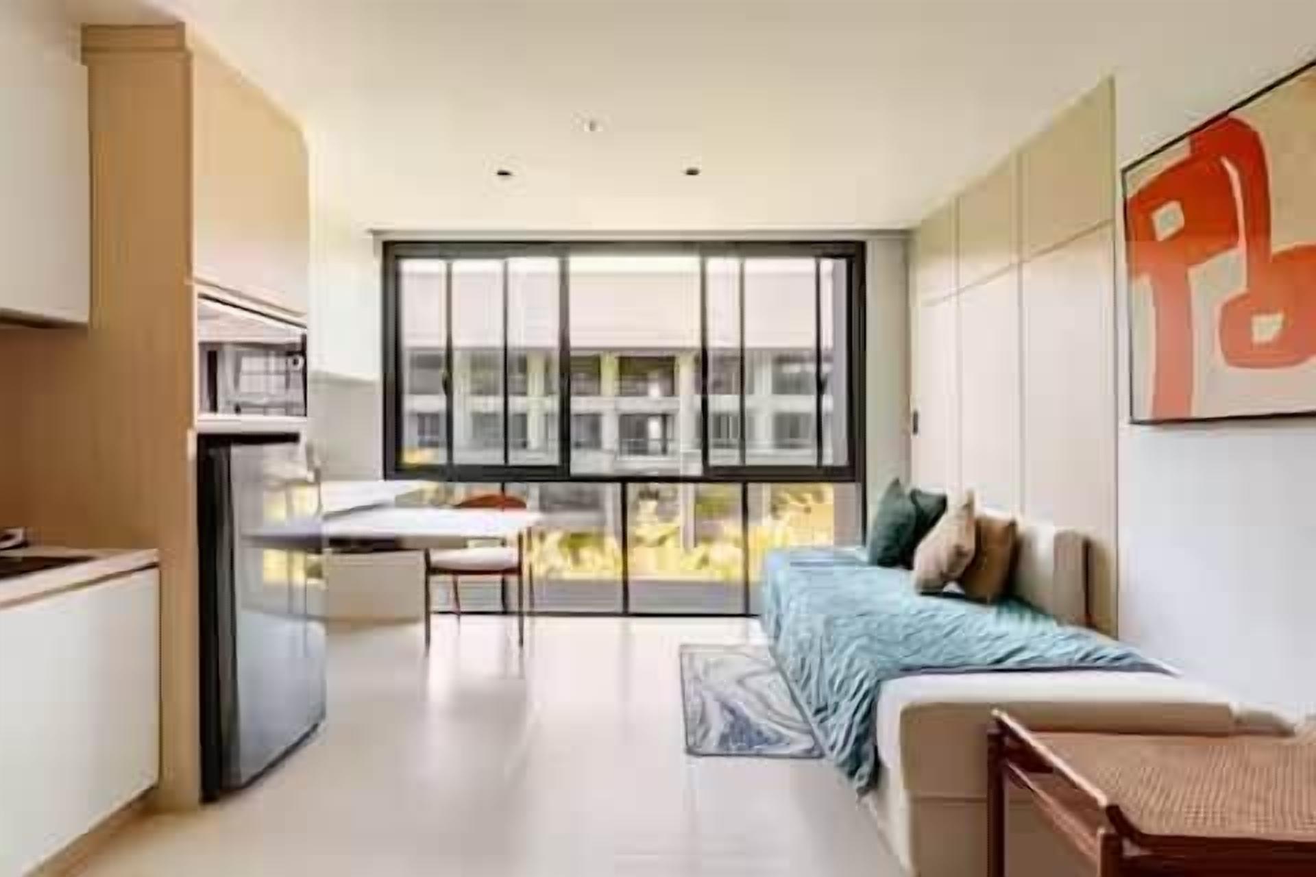 Een modern appartement met een kitchenette, een eethoek, een bank en een groot raam.